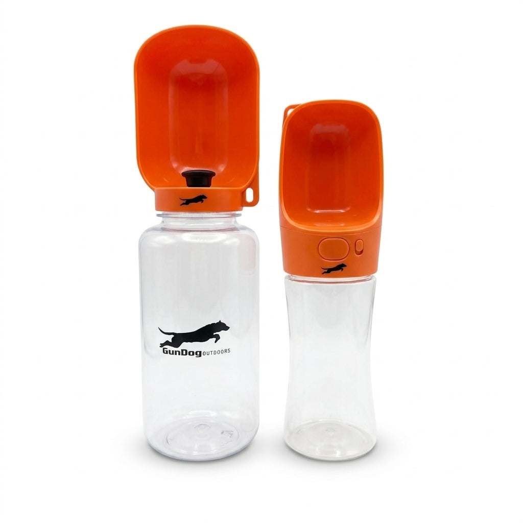 Two portable dog water bottles with bright orange spill-proof lids and clear plastic bodies, shown on a white background. One bottle is open and standing upright, and the other is closed and slightly angled.